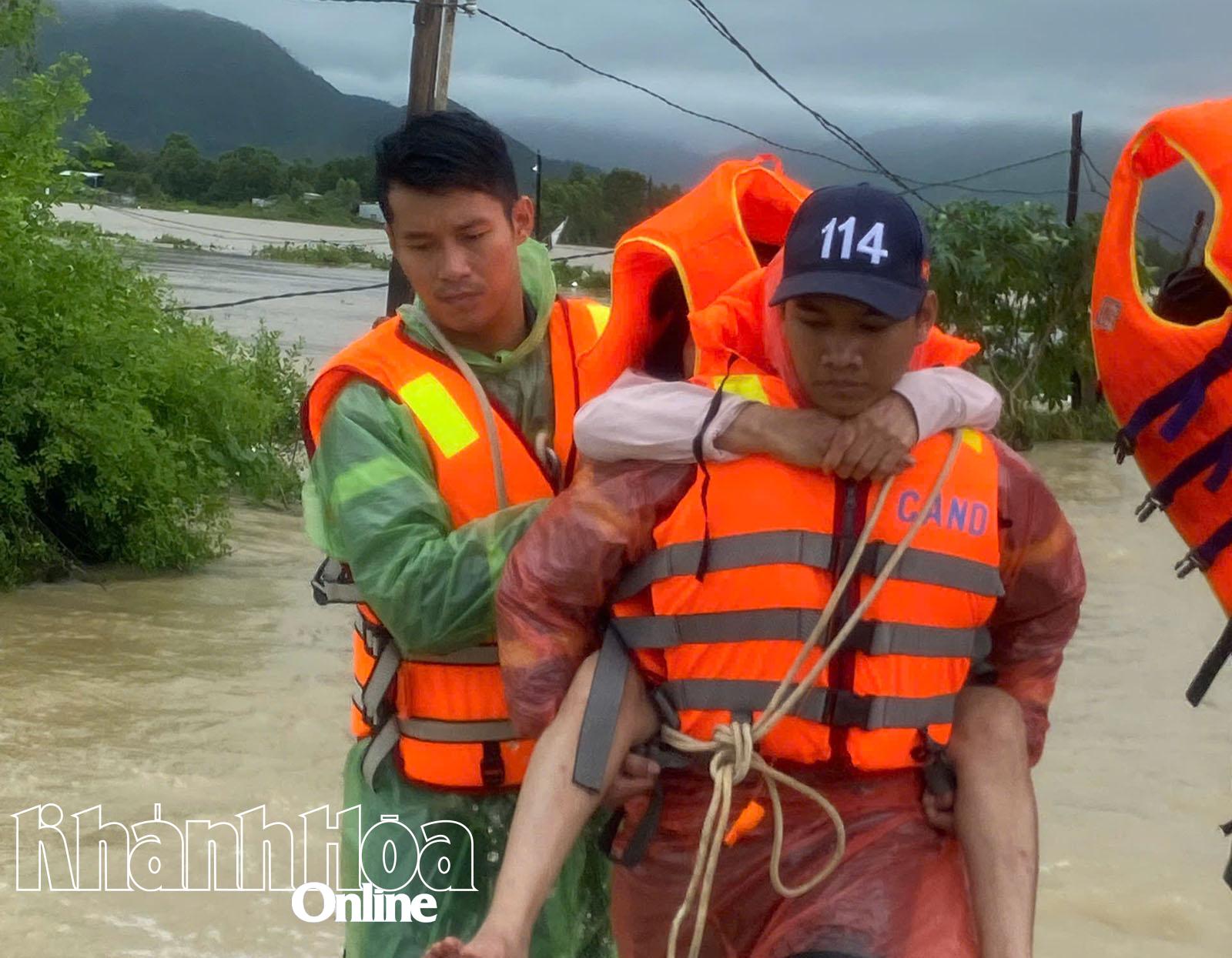 Các chiến sĩ cứu nạn, cứu hộ cõng một người dân ở vùng rốn lũ Tây Nha Trang thoát khỏi vùng nguy hiểm