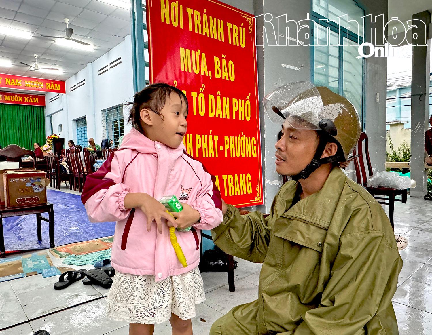 Tổ trưởng Tổ dân phố Thành Đạt trao sữa, trò chuyện với một em nhỏ tại điểm tránh trú ở Nhà văn hóa Tổ dân phố Thành Phát.