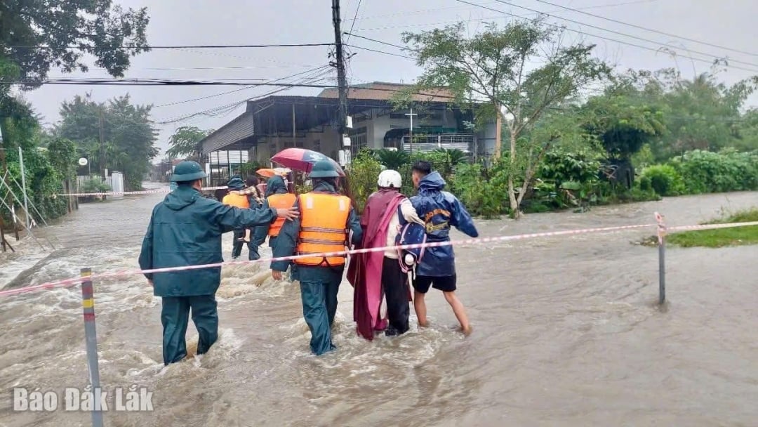 Die Behörden der Gemeinde Ea Phe unterstützen Menschen, die sich durch überschwemmte Gebiete bewegen.