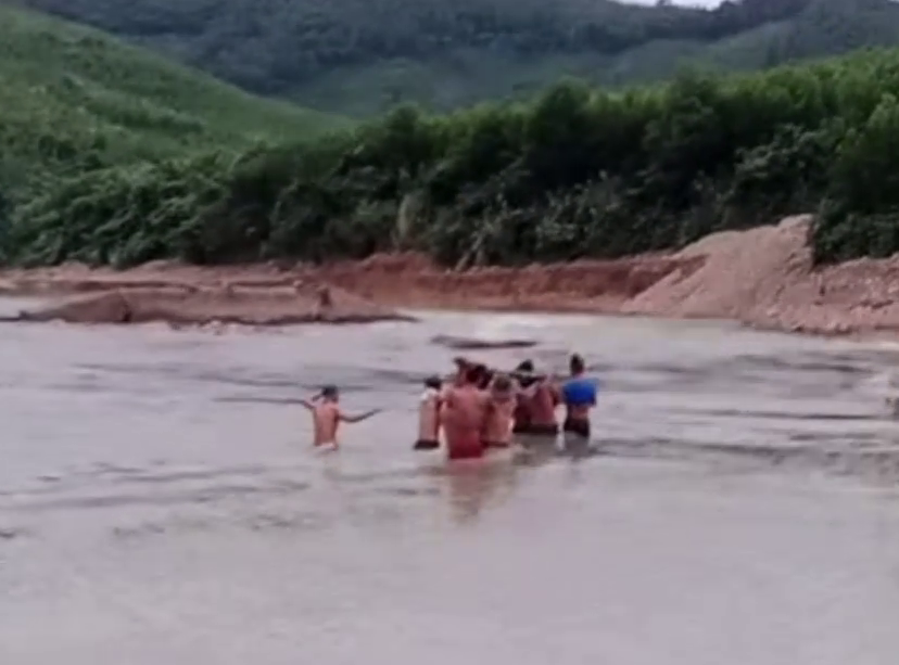 Dussintals unga män från byn Cat turades om att bära den gravida kvinnan i en hängmatta över bäckar och genom forsande vatten till sjukhuset för akutvård - Foto: klippt från klipp