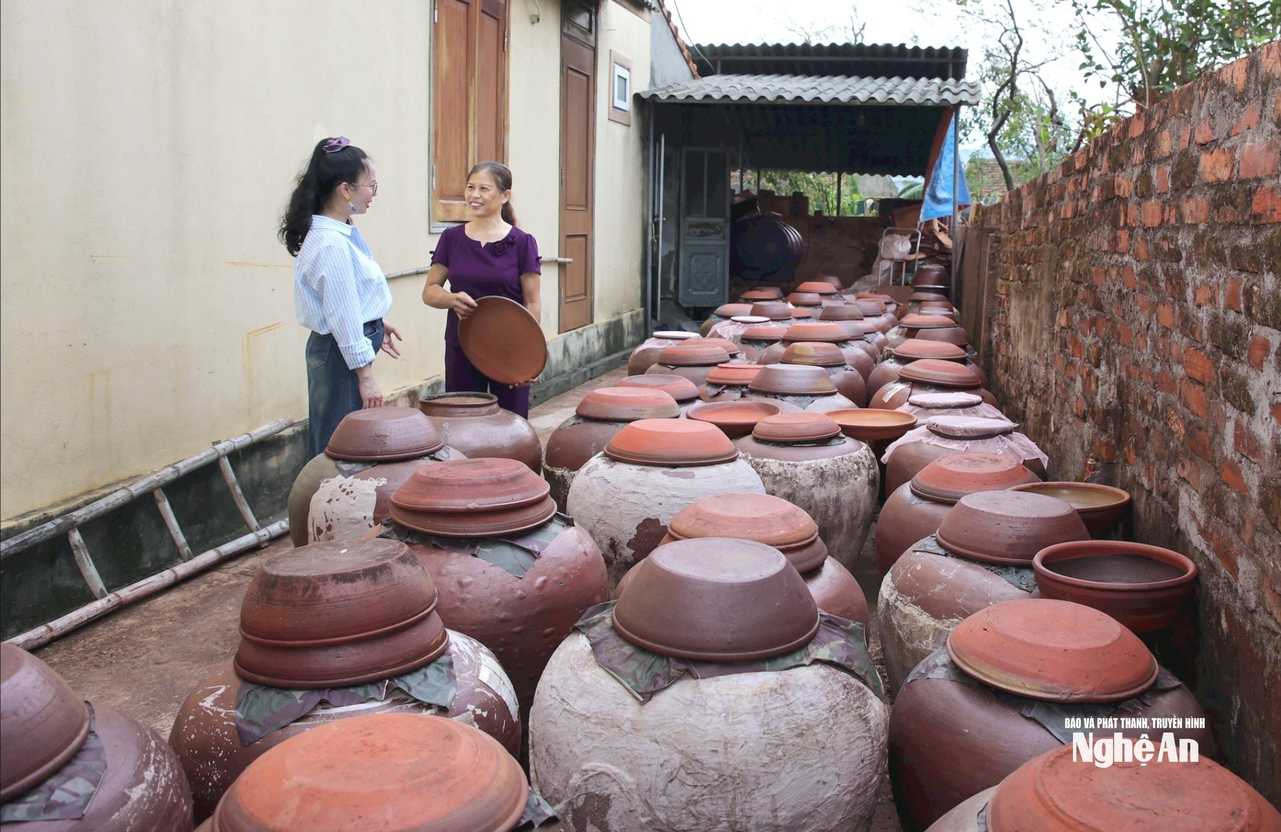 خانم بویی تی ها (متولد ۱۹۶۷، سمت راست تصویر) در دهکده ۴، بخش کیم لین، در کنار شیشه‌های سس سویای خانواده‌اش. عکس: تان کوئین