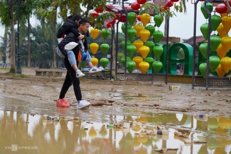 گردشگران خارجی در هوی آن از جاده‌ای گل‌آلود عبور می‌کنند.