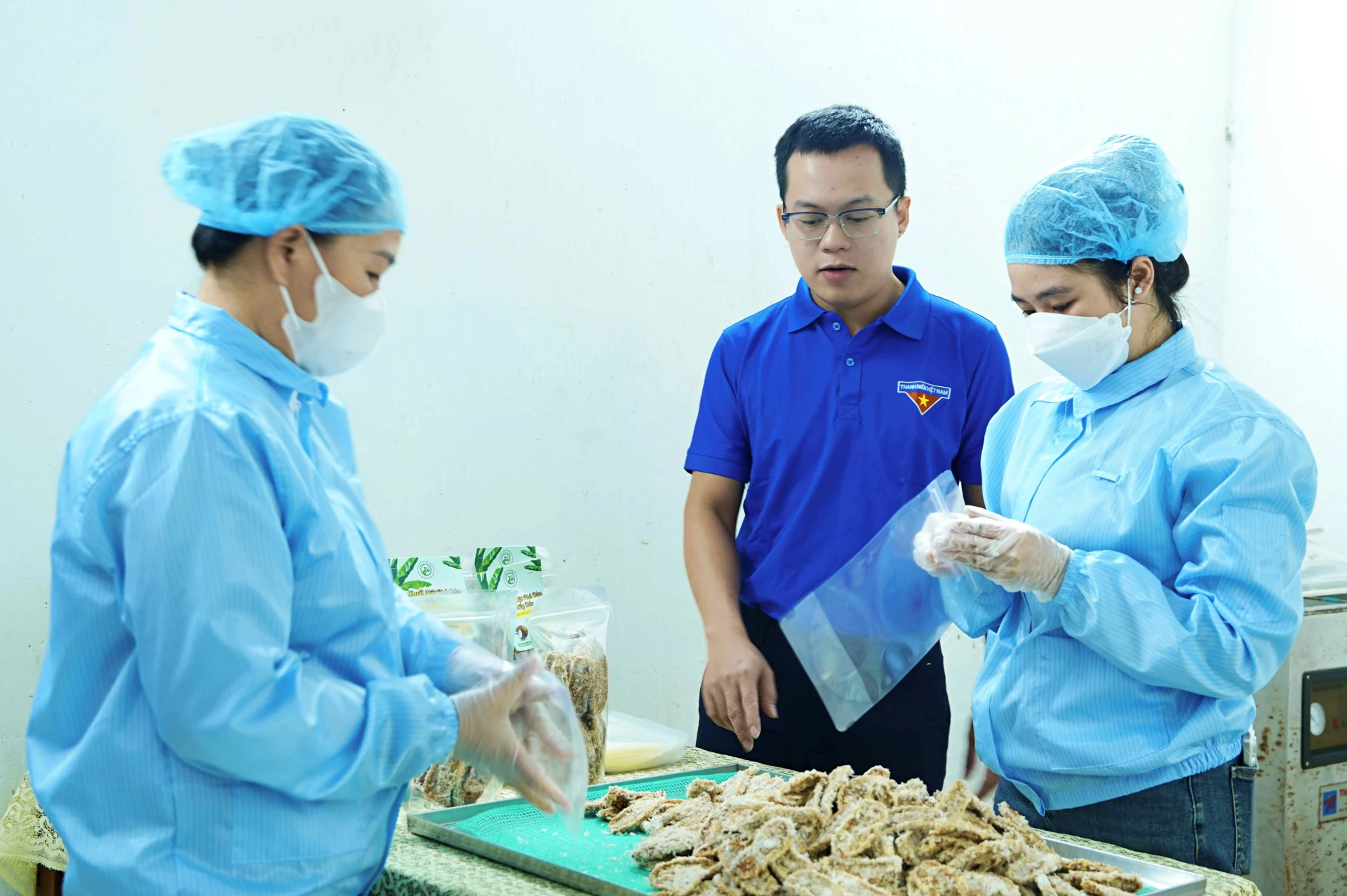 Bapak Hoang Huy Thanh memeriksa proses pengemasan produk pisang kering berlapis kelapa - Foto: Q.H