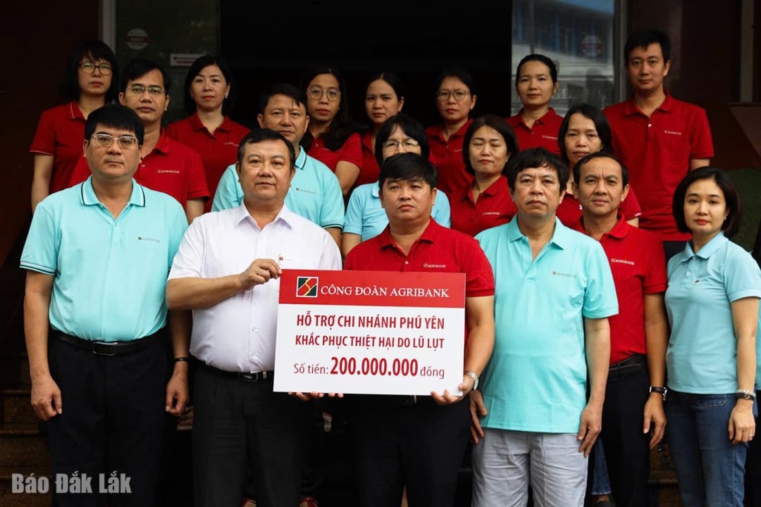 Herr Nguyen Tien Truong, leder for Agribanks representasjonskontor i den sentrale regionen (første rad, andre fra venstre), representant for Agribanks fagforening, overrakte 200 millioner VND i støtte for å hjelpe Agribank Phu Yen-filialen med å komme seg over flomskadene.