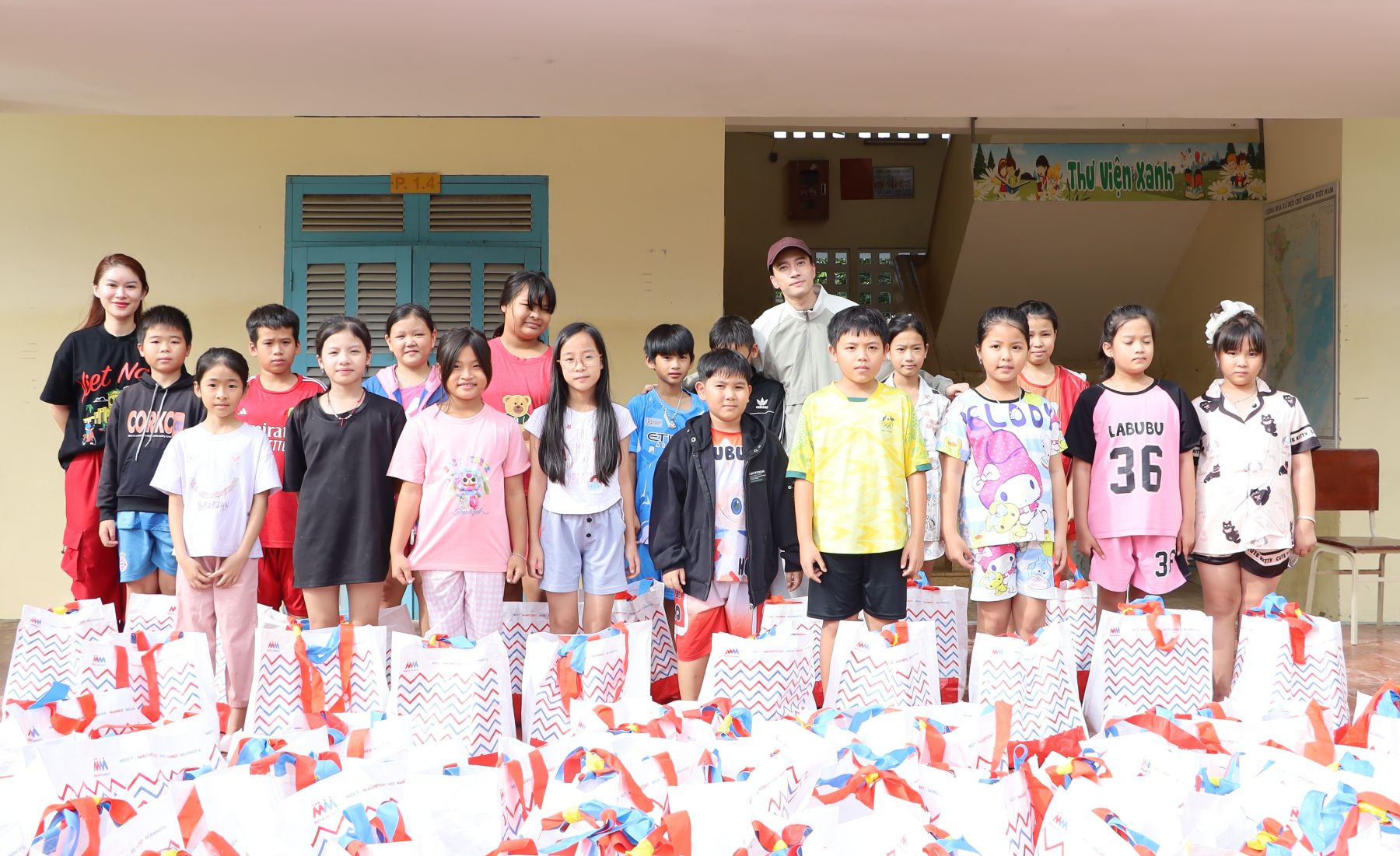 A atriz Ngoc Thanh Tam e o cantor S.T Son Thach entregam presentes aos alunos da Escola Primária Vinh Thai.