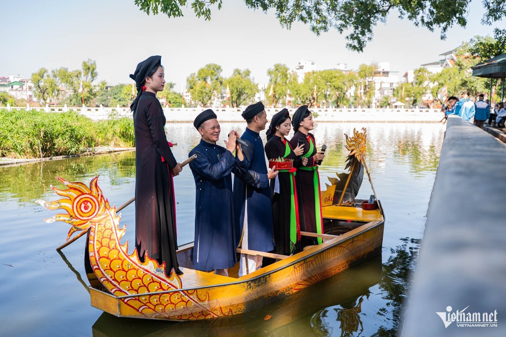 男性と女性の歌手がド寺院の水亭でクアンホー歌を披露しています。