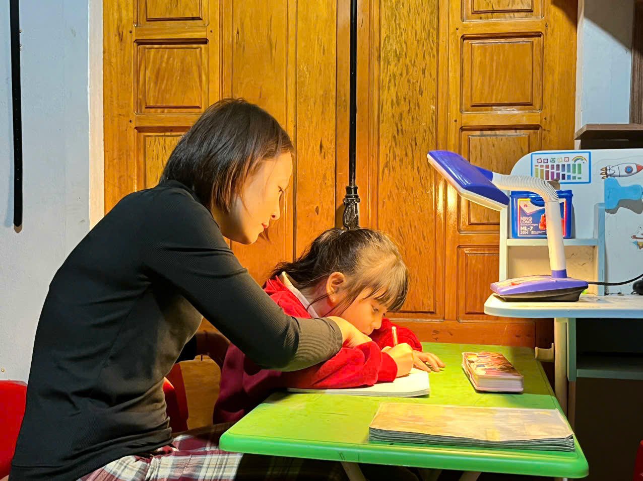 Mevrouw Cao Thi Kim Duyen (dorp Ha Luong) helpt haar kind, Nguyen Ngoc Thien An, klas 1A, met studeren op het juiste moment nadat de luidspreker het signaal uitzendt.