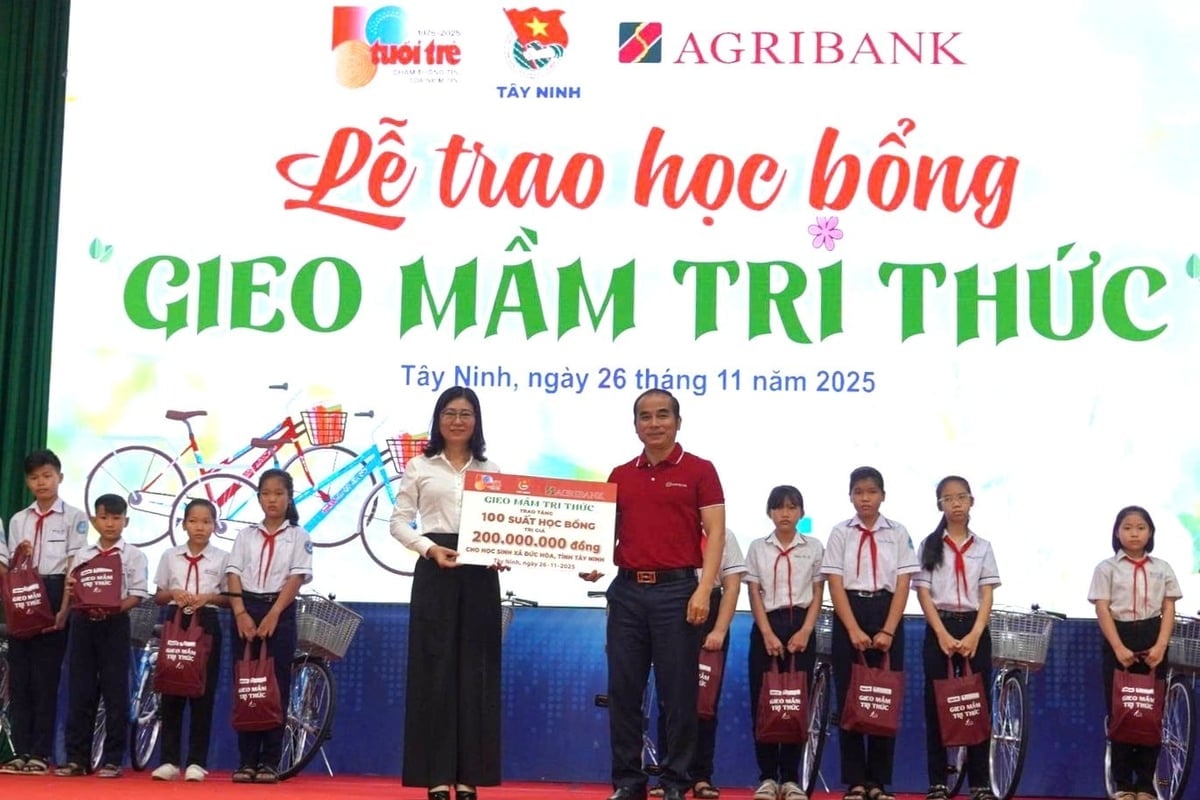 Ông Phạm Văn Hóa - Phó Giám đốc Agribank chi nhánh Phú Nhuận (áo đỏ) trao bảng tượng trưng tặng học bổng 'Gieo mầm tri thức' cho xã Đức Hòa (tỉnh Tây Ninh). Ảnh: Minh Khương.