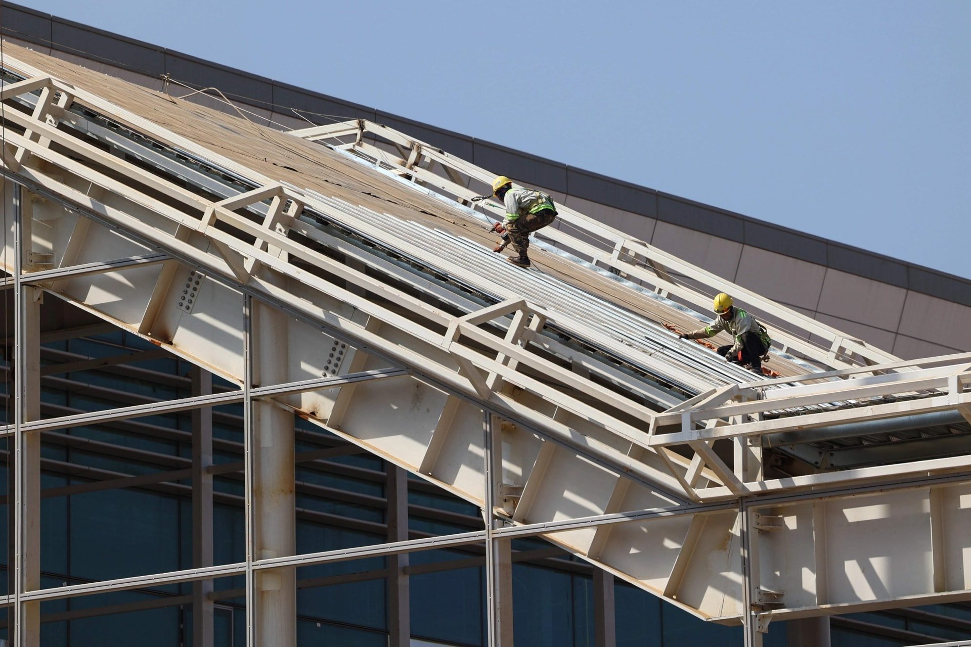 Крани піднімають компоненти для встановлення телескопічного мосту на будівельному майданчику.