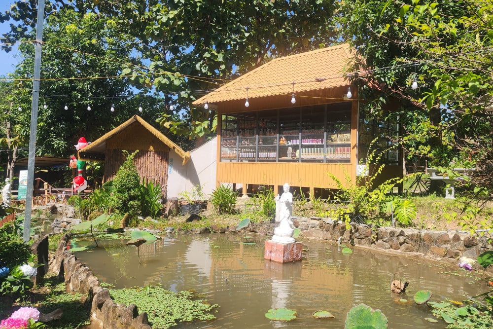 : Hồ nhân tạo và công trình nhà giả gỗ bày bán hàng hóa bên bờ suối