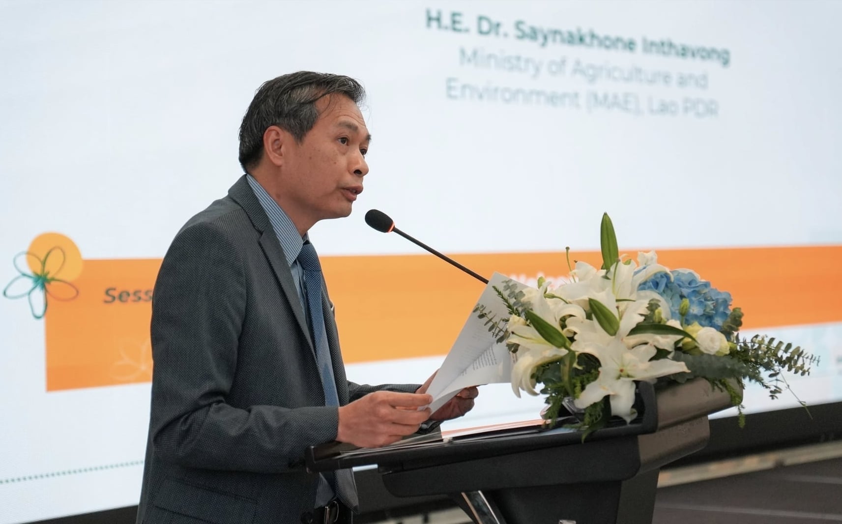 លោក Saynakhone Inthavong អនុរដ្ឋមន្ត្រីក្រសួងកសិកម្ម និងបរិស្ថាននៃប្រទេសឡាវបានថ្លែងសុន្ទរកថាបើកនៅក្នុងសន្និសីទអន្តរជាតិស្តីពីកសិកម្មអេកូឡូស៊ី និងកសិកម្មបង្កើតឡើងវិញ។ រូបភាព៖ គណៈកម្មាធិការរៀបចំ។ Ông Saynakhone Inthavong, Thứ trưởng Bộ Nông nghiệp và Môi trường Lào, phát biểu khai mạc Hội nghị quốc tế về Nông nghiệp sinh thái và Nông nghiệp tái sinh. Ảnh: BTC.