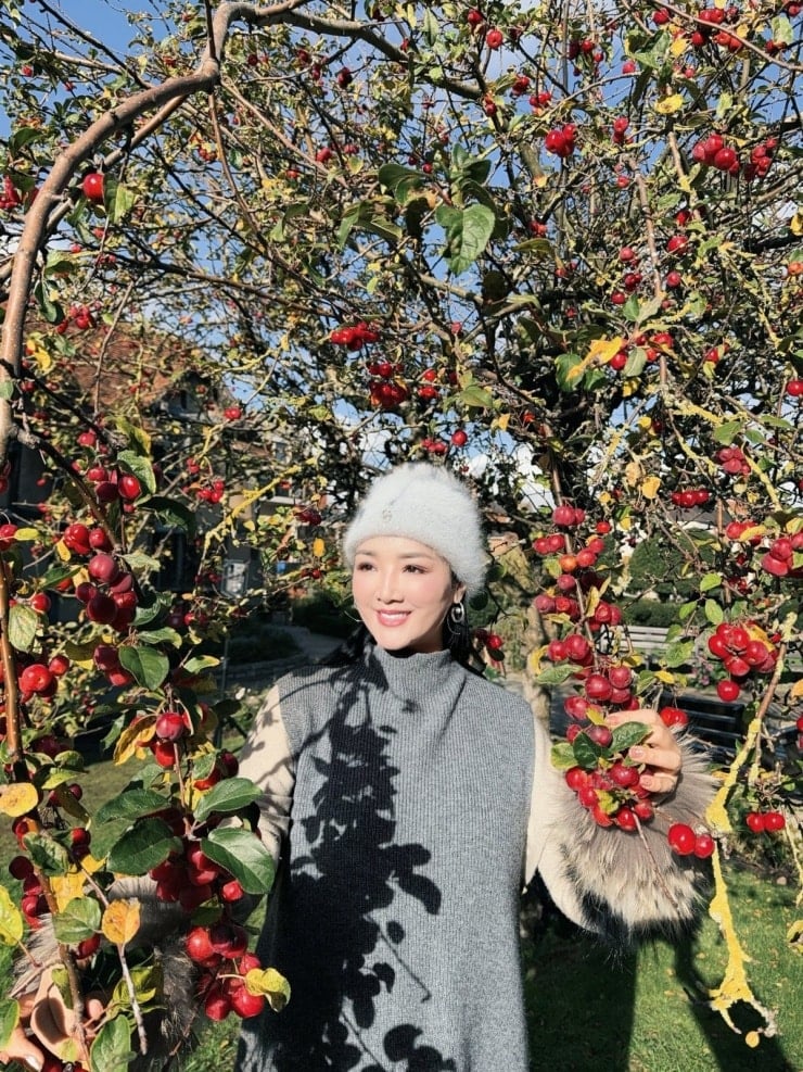 Ein Tourist posiert neben der ikonischen roten Telefonzelle im Dorf Castle Combe.