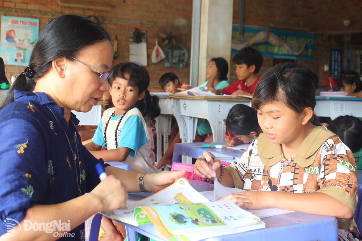 Syster Teresa Pham Thi Kim Lan betygsätter uppsatser för barn i välgörenhetsklassen i 