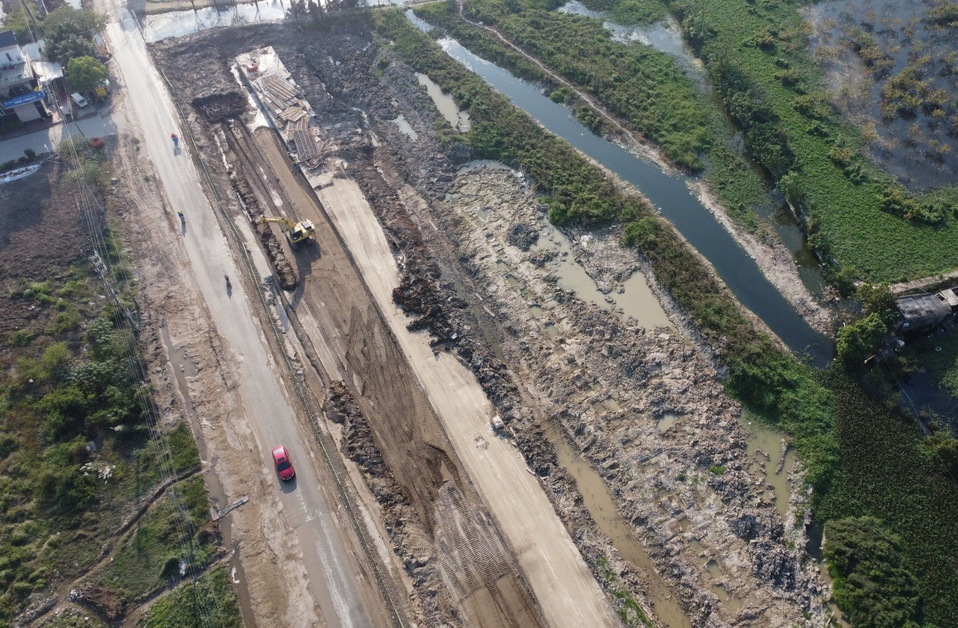 作業員と機械が地面を平らにし、排水システムを設置しています。