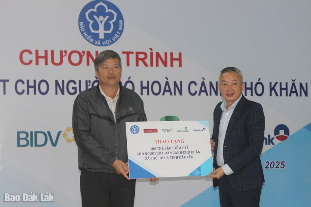 Herr Tran Manh Toan, chef för den provinsiella socialförsäkringen (höger), överlämnade logotypen för 100 sjukförsäkringskort till invånarna i Phu Hoa 2 kommun.