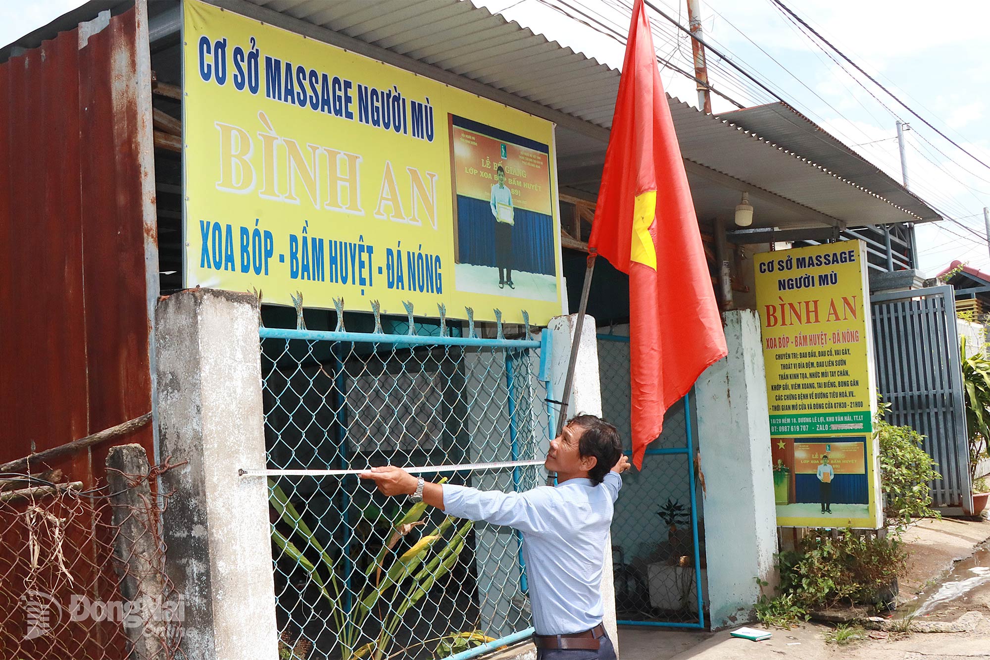 Herr Nguyen Van Thinh måler dimensjonene for å reparere reklameskiltet for blindemassasjeanlegget Binh An, eid av herr Do Van Binh. Foto: Quang Minh