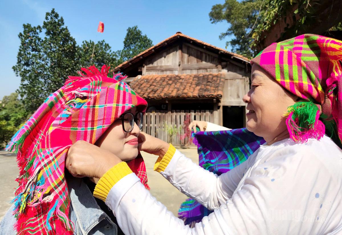 ซิสเตอร์มา กำลังสาธิตวิธีการพันผ้าคลุมศีรษะแบบดั้งเดิมของชาวม้งให้แก่นักท่องเที่ยวดู