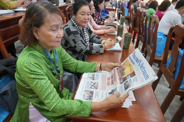 ผู้แทนอ่านหนังสือพิมพ์สตรีเวียดนามก่อนเปิดการประชุม Đại biểu đọc báo Phụ nữ Việt Nam trước giờ khai mạc đại hội