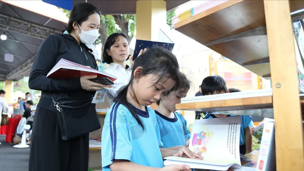 កុមារ និងមនុស្សពេញវ័យកំពុងមើលសៀវភៅនៅឯពិព័រណ៍សៀវភៅមួយក្នុងទីក្រុងហូជីមិញ។ រូបថត៖ QUYNH YEN