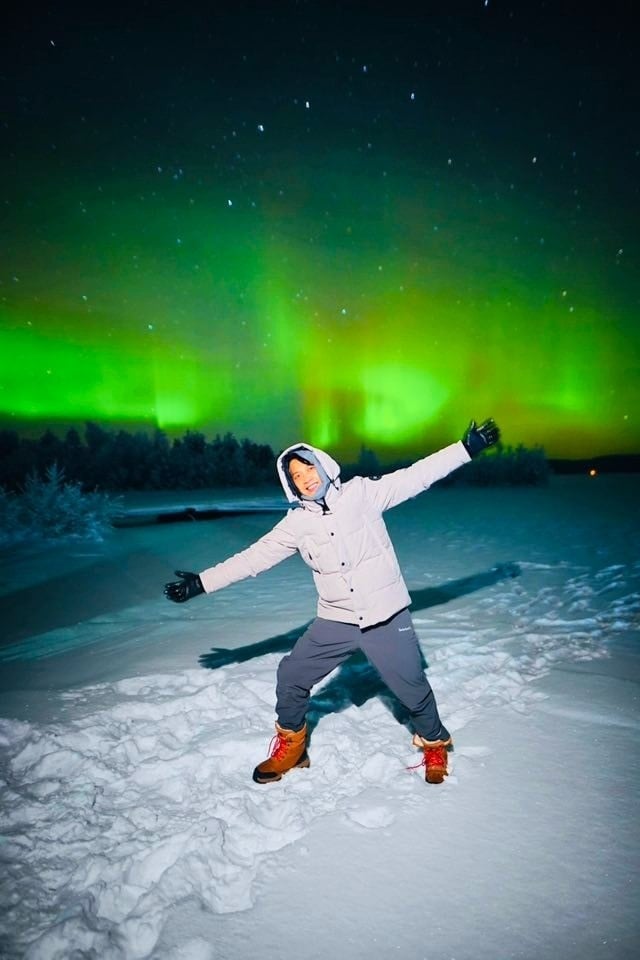 گردشگران، با لباسهای گرم، به شفق قطبی خیره شدهاند.