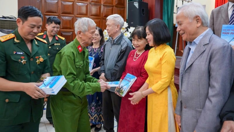 A veterana de guerra e professora Nguyen Thuy (fila de cima, segunda da esquerda) entrega seu diário de guerra a um leitor.