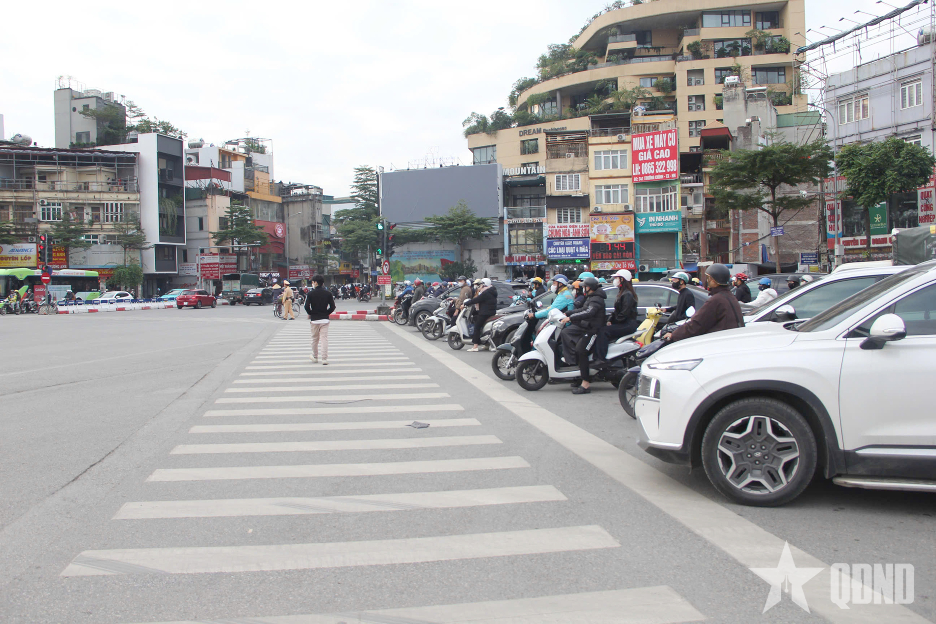 Na snímku jsou vidět lidé zastavující na červenou ráno 15. prosince na křižovatce O Cho Dua v Hanoji.