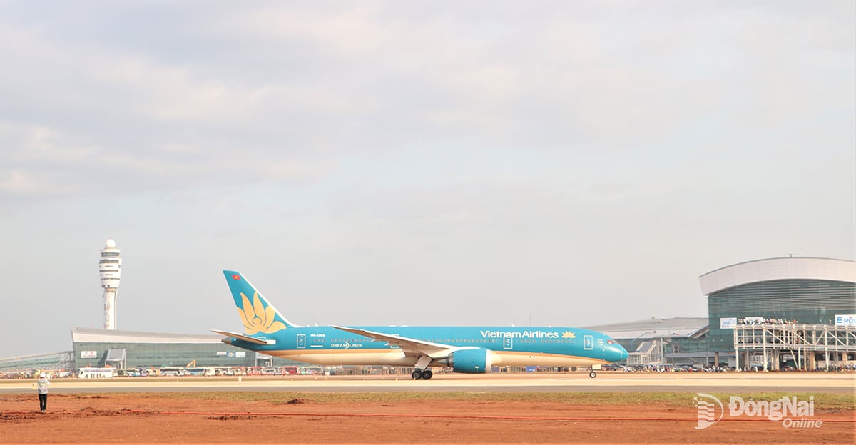 L'avion passe devant le terminal passagers, avec la tour de contrôle de l'aéroport de Long Thanh à l'arrière.