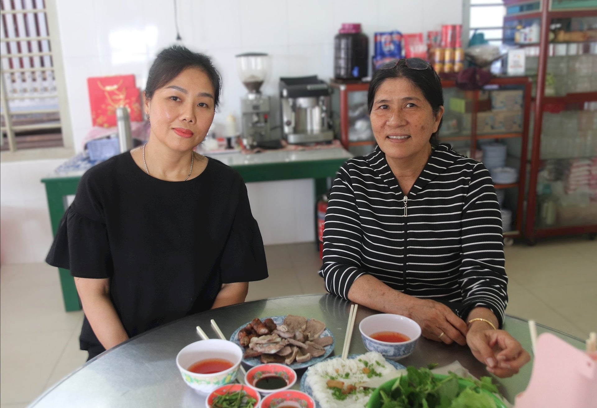 La signora Bui Xuan Thao, proprietaria del negozio di noodle di riso con frattaglie di maiale di Quynh (a sinistra), parla con la signora Ho Thi Thu Van di come mantenere il marchio di questo piatto per la colazione che attrae molti clienti.
