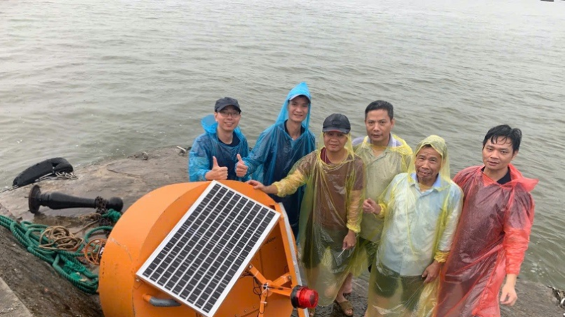 Gambar tersebut menunjukkan tim yang sedang melaksanakan proyek pemasangan dan pengujian sistem pemantauan otomatis di Pulau Hon Dau.