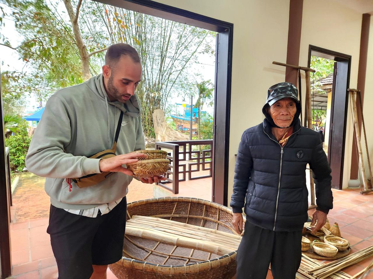 Craft villages must constantly improve their designs to suit market tastes in order to survive. In the photo: Tourists learn about souvenirs from Cam Kim weaving. Photo: QUOC TUAN