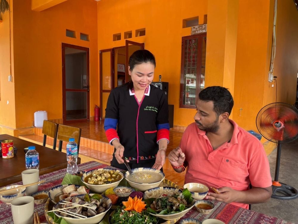 Los turistas extranjeros experimentan la cocina indígena del pueblo Dao. Foto: Khanh Dan