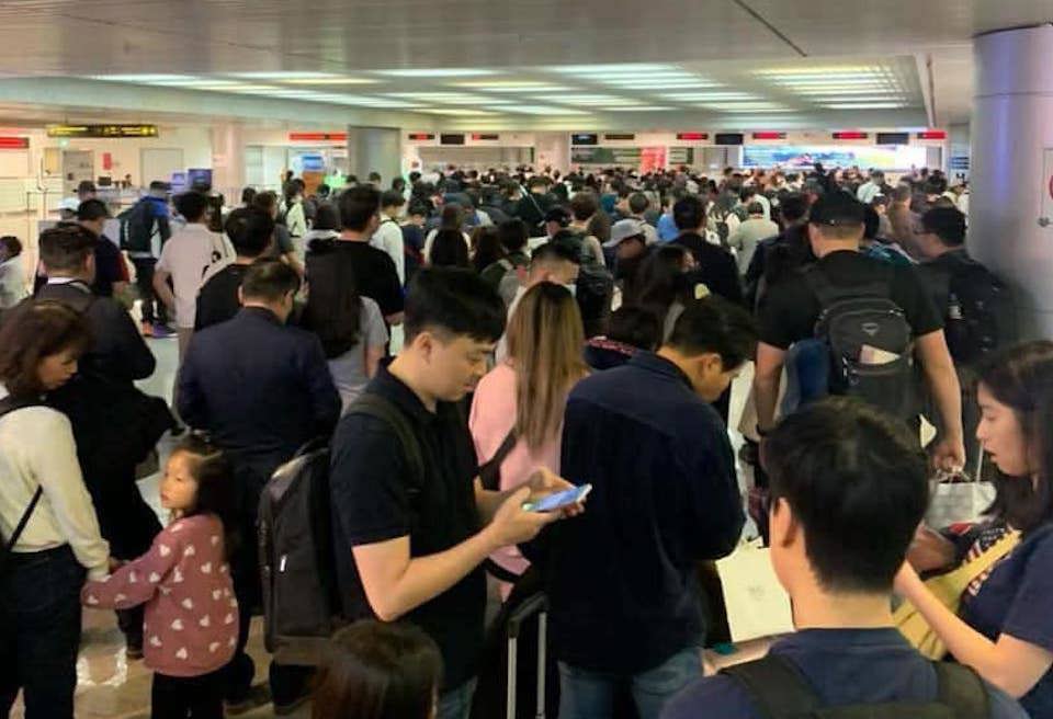 Tired passengers wait to get their checked baggage at Tan Son Nhat airport