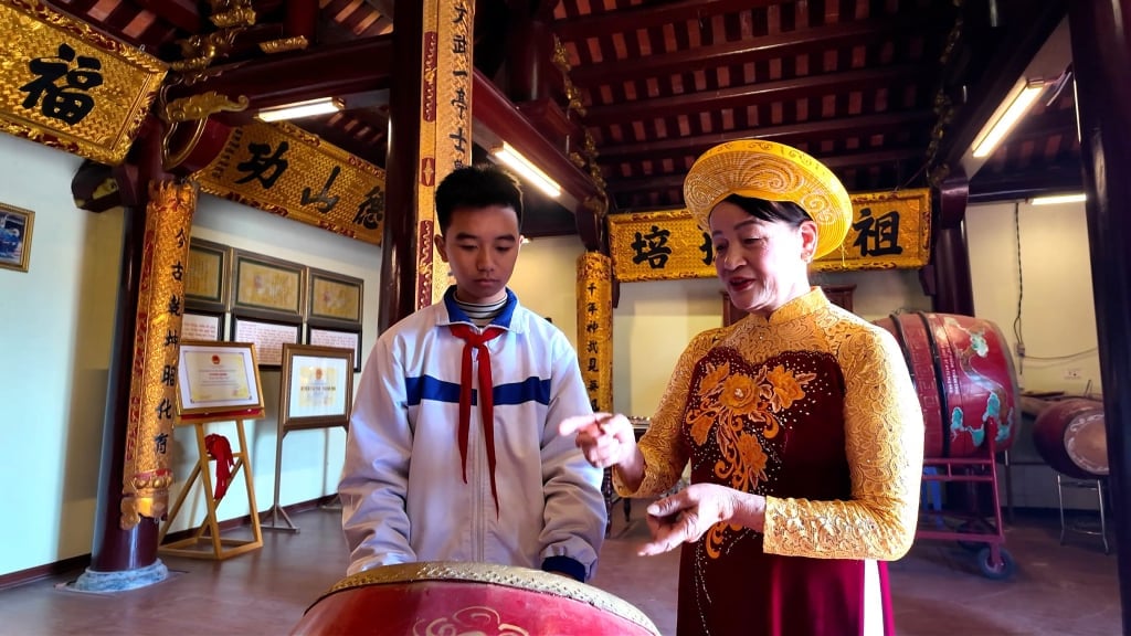 Artist Le Thi Loc teaches how to beat the drum in the communal house singing and dancing performance.