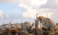 Junge Leute checken am einzigartigen Felsstrand in Da Nang ein, um den Sonnenaufgang und Sonnenuntergang zu beobachten