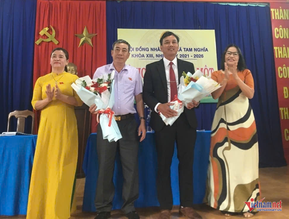 Foto: La Sra. Huynh Thi Tu, con un ao dai amarillo y presidenta del Consejo Popular de la Comuna de Tam Nghia, entregó flores para felicitar al Sr. Bui Quoc Bieu (traje) y al Sr. Nguyen Thanh Dat (camisa blanca).