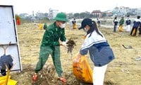 Border guards and youth union members clean the beach