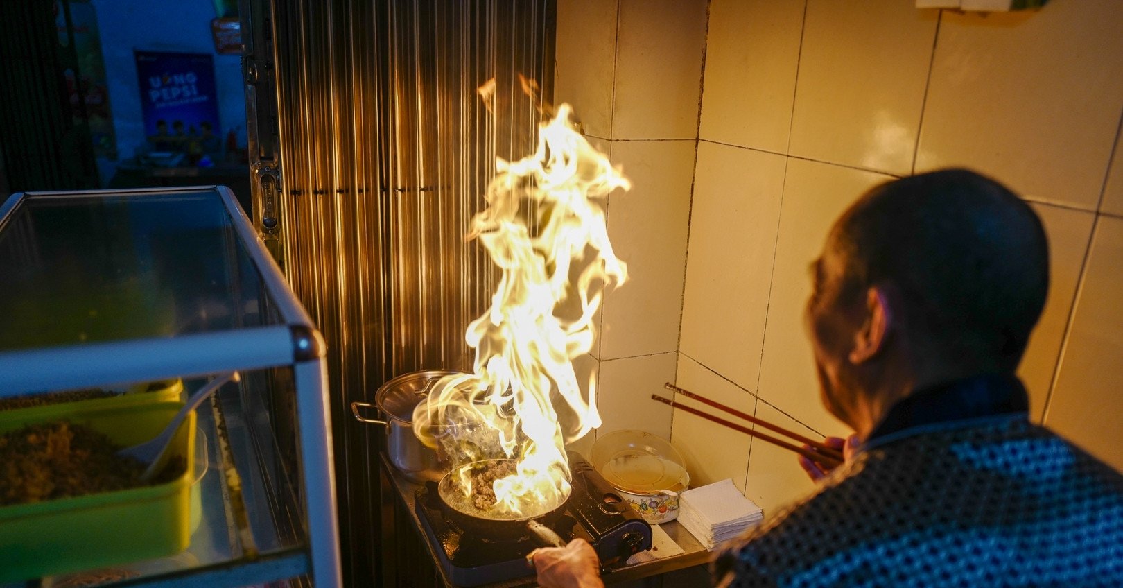 Customers squeeze through narrow alleys to find the owner of the beef noodle shop who skillfully 'dances fire' in Hanoi