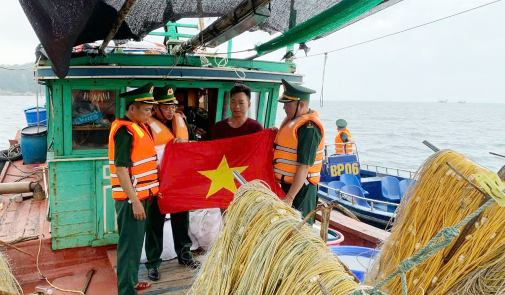 Les agents du poste de garde-frontière de l'île de Tran présentent des drapeaux nationaux aux pêcheurs qui partent en mer.