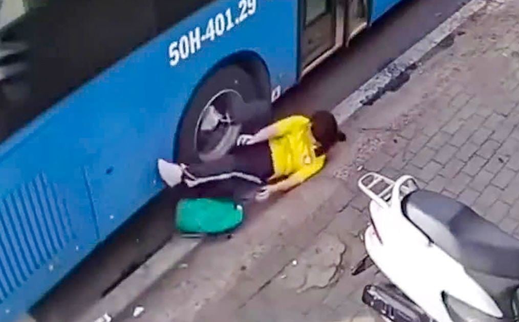 Scène à couper le souffle d'une étudiante presque coincée sous une roue de voiture parce que son sac à dos est coincé dans la porte du bus