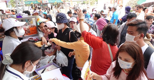 Ein Meer von Menschen steht in der Sonne und wartet darauf, in HCMC Brot zu kaufen