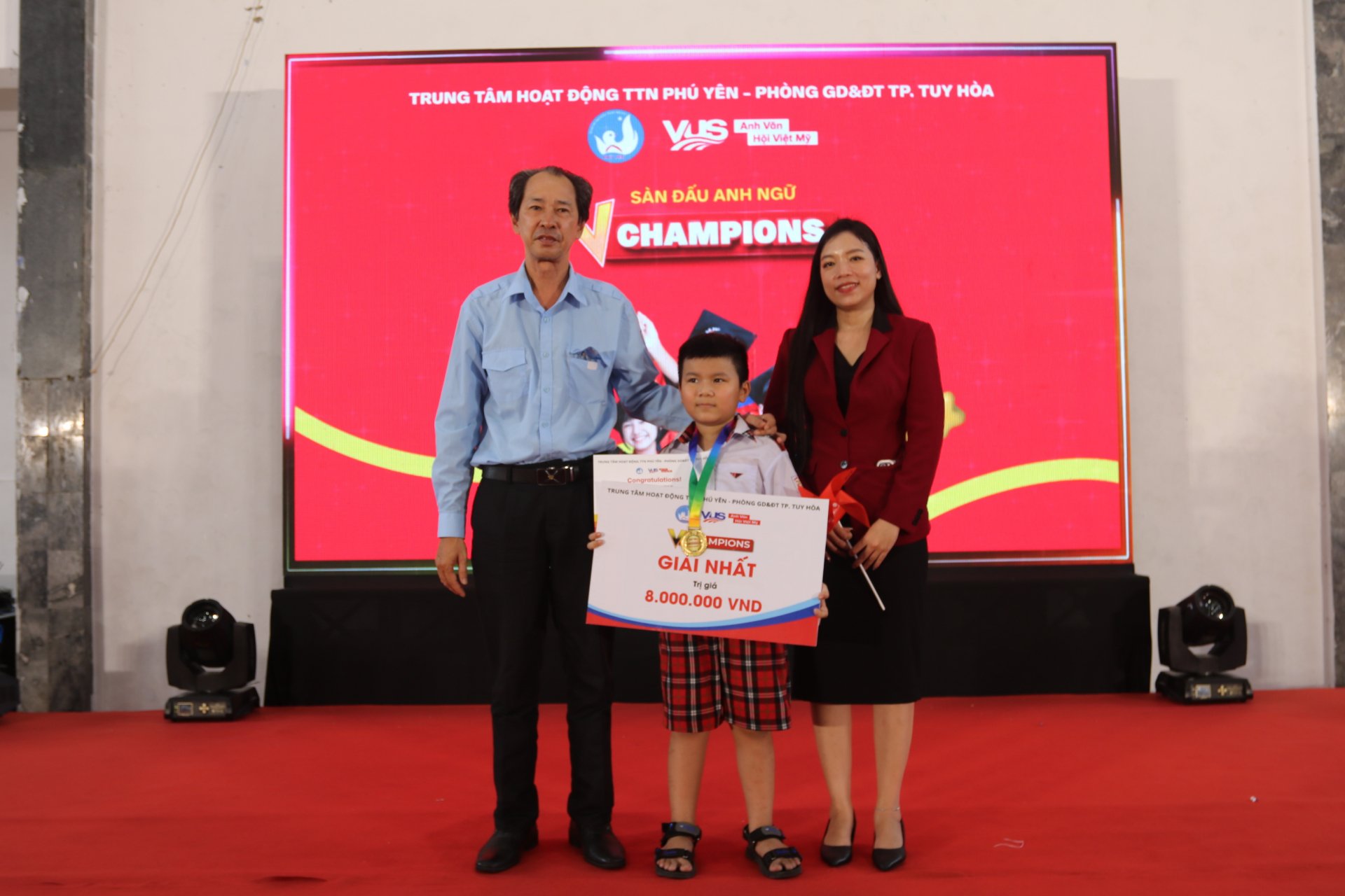 Lãnh đạo Trung tâm Hoạt động thanh thiếu nhi Phú Yên, đại diện Anh văn Hội Việt Mỹ VUS trao giải nhất khối lớp 3 cho Nguyễn Hoàng Phi Long. Ảnh: KIỀU MY