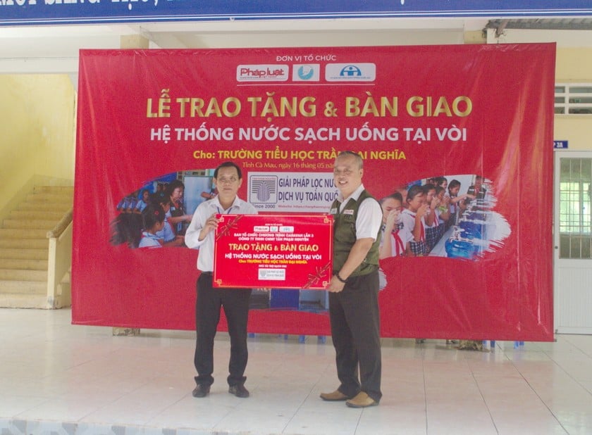 Ông Trương Quang Vũ - Phó Giám Đốc Công ty TNHH Công nghệ Môi trường Tân Phạm Nguyên (bên phải), trao bảng tượng trưng và bàn giao Hệ thống lọc nước lọc cho Thầy Nguyễn Minh Đoàn - Hiệu trưởng Trường Tiểu học Trần Đại Nghĩa.
