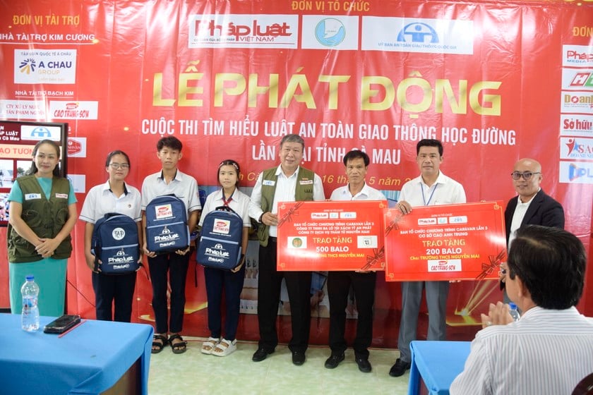 Ông Nguyễn Văn Nam – Đại diện phía Nam, Ban Truyền thông Đa phương tiện Báo Pháp luật Việt Nam, Phó Ban tổ chức Thường trực Đoàn Caravan (bên trái) cùng nhà tài trợ (bên phải) trao tặng bảng tượng trưng 700 ba lô cho học sinh Trường THCS Nguyễn Mai.