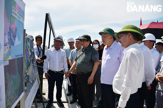 Thủ tướng Chính phủ Phạm Minh Chính (thứ 3, bên phải sang) nghe Giám đốc Ban quản lý các dự án đầu tư cơ sở hạ tầng ưu tiên thành phố Lê Thành Hưng báo cáo tiến độ dự án Cảng Liên Chiểu (triển khai thi công trên địa bàn quận Liên Chiểu). Ảnh: THÀNH LÂN