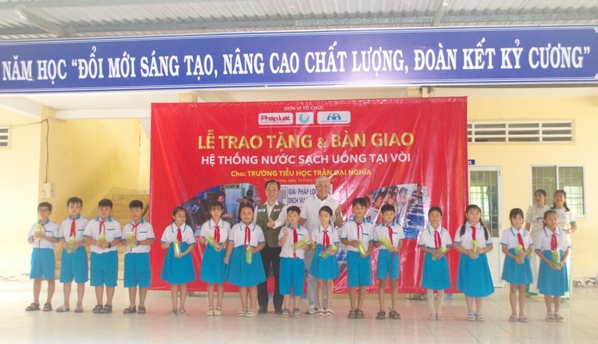 Đại diện Ban Tổ chức Chương trình Caravan Báo Pháp luật Việt Nam và Diễn viên Tùng Yuki - Đại sứ Đoàn Caravan (áo trắng) trao tặng tượng trưng và bình nước cá nhân cho các em học sinh.