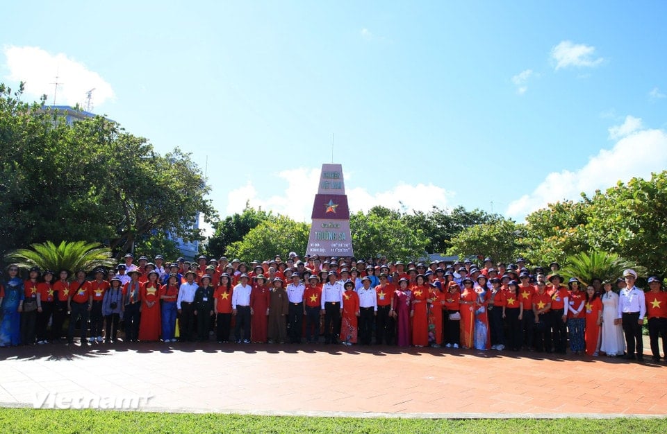 Working Group No. 13 takes a souvenir photo at the sovereignty marker on Truong Sa Island. (Photo: Huy Khanh/Vietnam+)