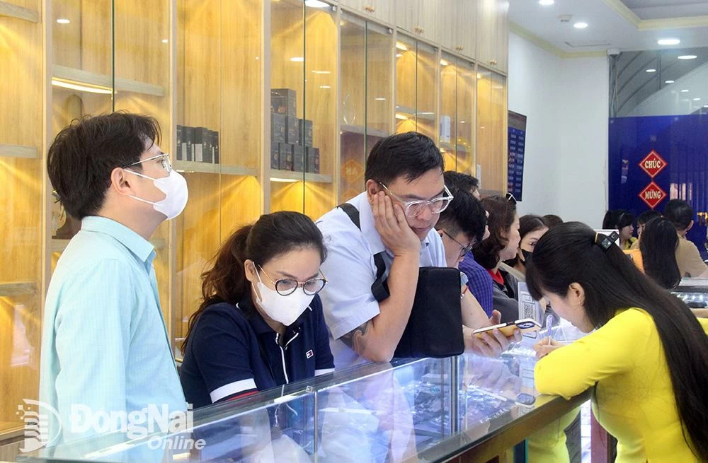 Menschen schauen sich die Goldpreise in einem Schmuckzentrum in der Stadt Bien Hoa an. Foto: Marine