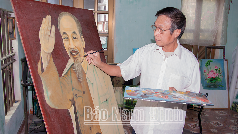 Artisan Dinh Khac Tuyen from Cat Dang village, Yen Tien commune (Y Yen) next to a painting of Uncle Ho.