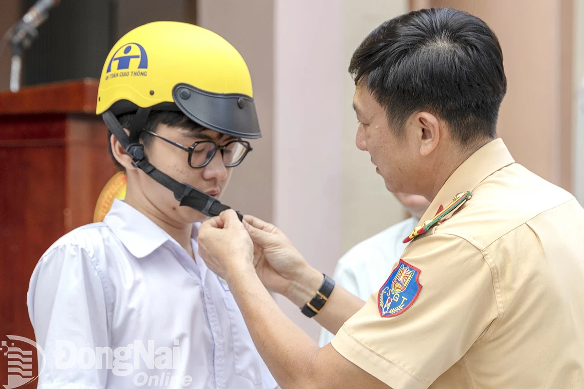 Lực lượng cảnh sát giao thông hướng dẫn cho học sinh tại thành phố Biên Hòa đội mũ bảo hiểm đúng cách.