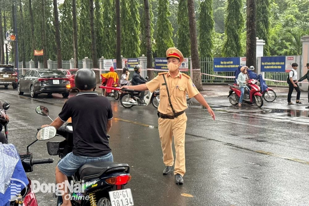 Lực lượng cảnh sát giao thông hướng dẫn phụ huynh dừng, đậu xe đúng nơi quy định trước hội đồng thi Trường THPT Long Thành (huyện Long Thành). Ảnh: Đăng Tùng